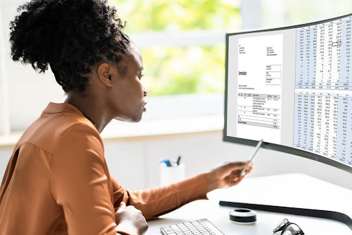 Woman in a healthcare office reviewing medical billing information on a computer screen.