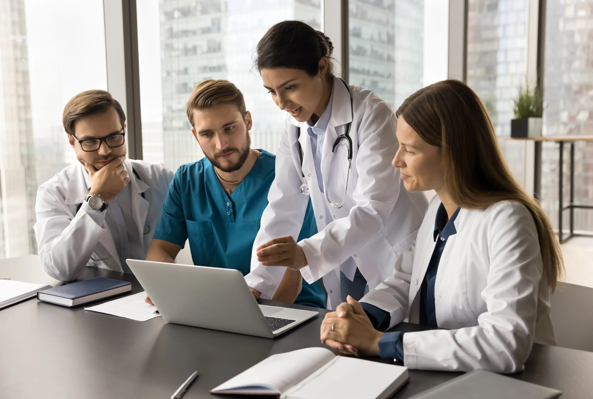 Doctors, nurses, and administrator reviewing files over laptop.