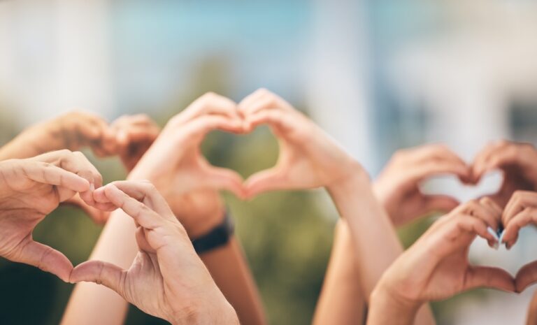 Hands raised in the air making heart shapes.